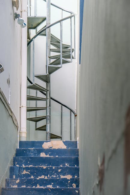 A narrow outdoor staircase made of stone steps ascending between residential buildings in Kennington, with brick and stucco facades. On the left, a white building features window shutters and decorati